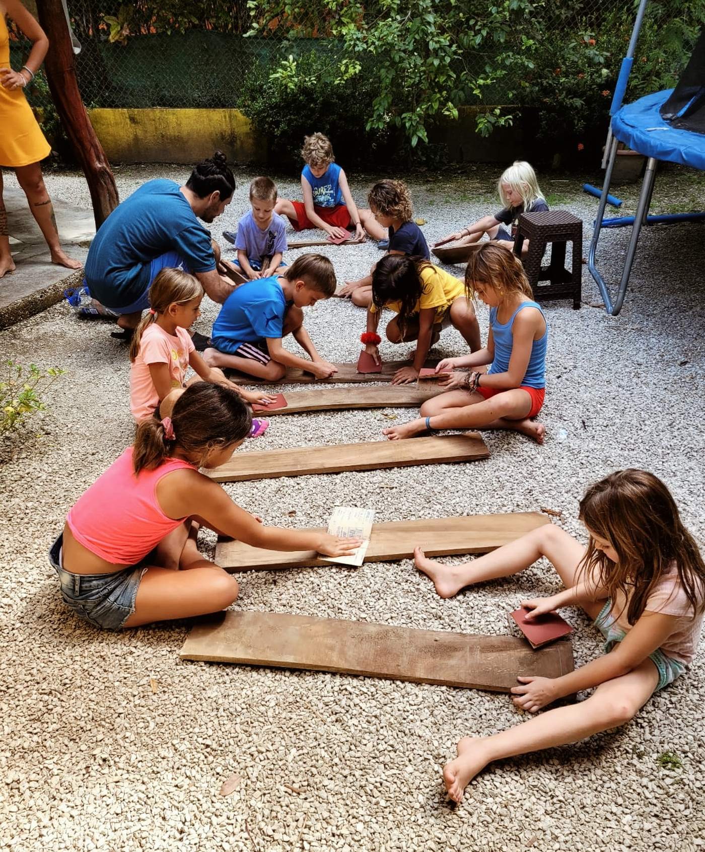 Children sanding wooden boards together in the school yard